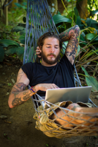 Man lying in hammock with laptop